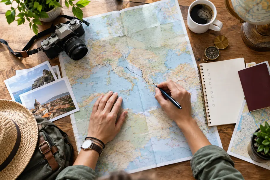 Traveler planning a route using a map, notebook and camera