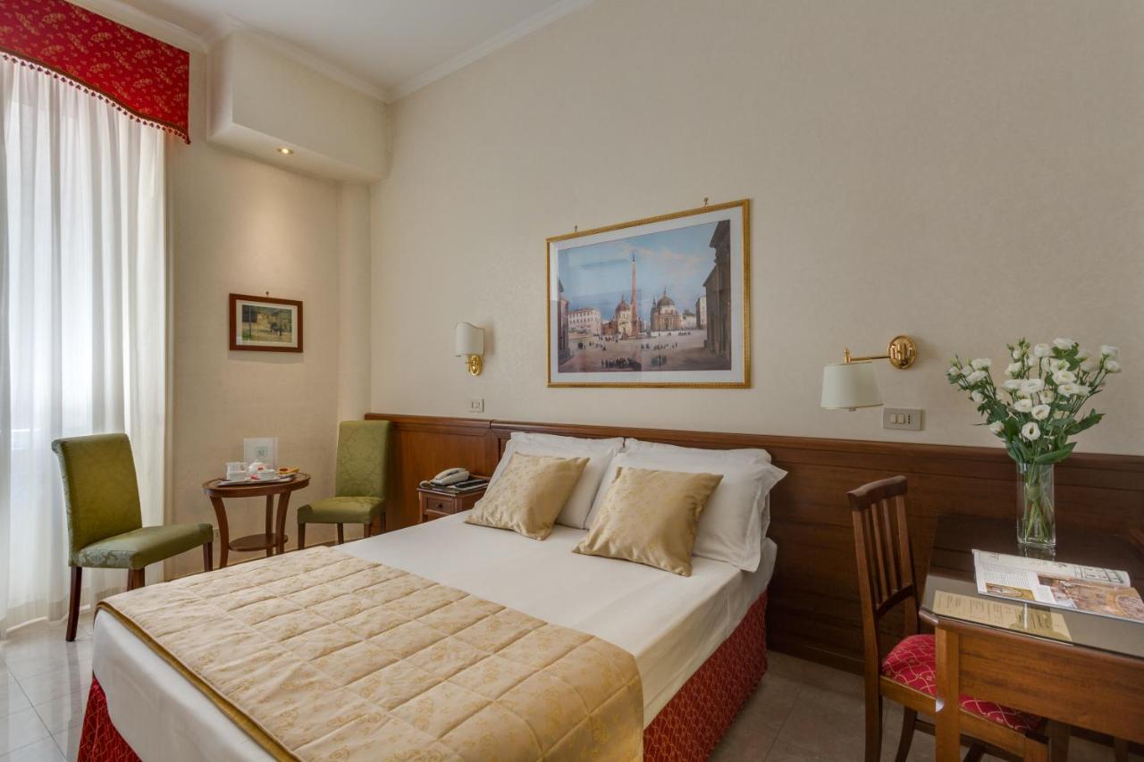 hotel room with gold bedspread on double bed, small wood desk, and red valence over window