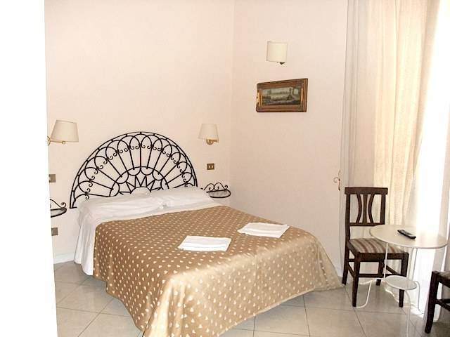 hotel room with gold bedding and wrought iron bed frame at Marta Guest House