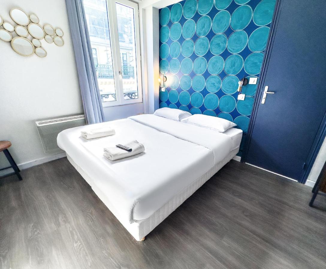 hotel room with white bed, blue wallpaper, and large window